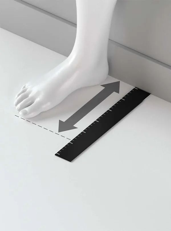 Pé sobre uma folha de papel encostada na parede, com uma régua ao lado